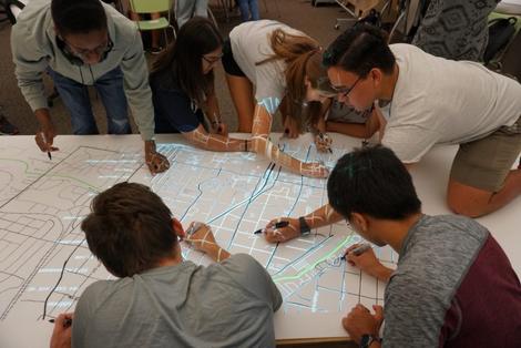 Students work on a map with digital overlay.