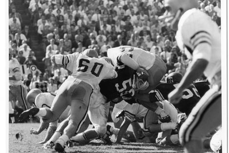 Vintage photograph of a Georgia Tech football game, capturing a tackle with the crowd in the background.