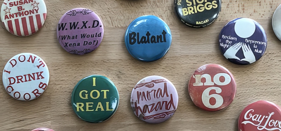 A selection of queer-themed buttons on a desk