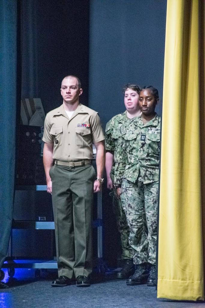 students stand on the side of the stage waiting to enter