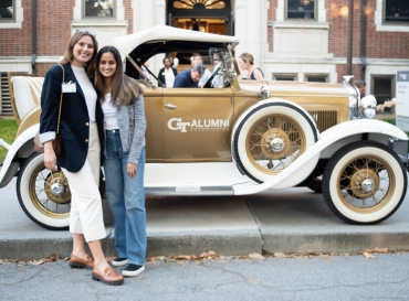 Two Public Policy alumni stand in front of the Ramblin' Wreck.