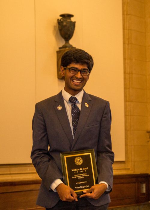 Vikas posing with an award plaque 