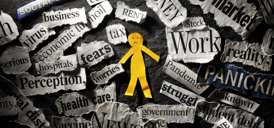 A yellow paper cutout of a person sits among cut-out paper with words such as "work," "virus," and other pandemic-related terms.