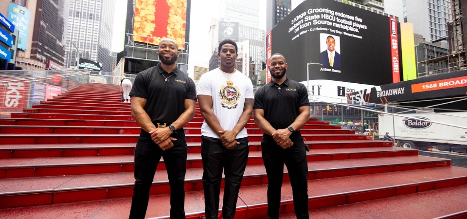 Antwan Owens, center, poses in Times Square on the day he signed his NIL deal.