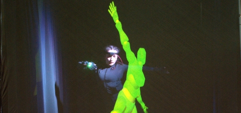 A Kennesaw State University dance student wearing motion capture gear and the LuminAI-powered avatar dance together.