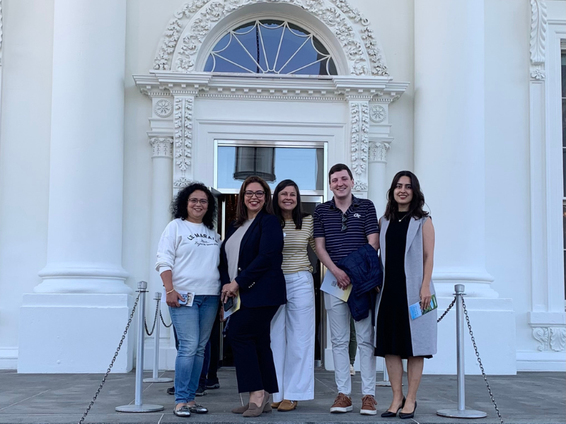 A group of visitors pose together outside the front door to the White House