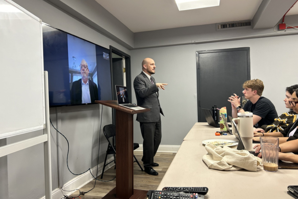 An instructor presents to the class, with Gen. Philip Breedlove on the screen adjacent to him.