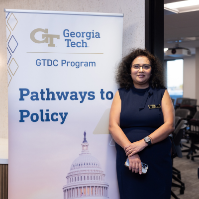 Participant stands next to a "Pathways to Policy" banner.