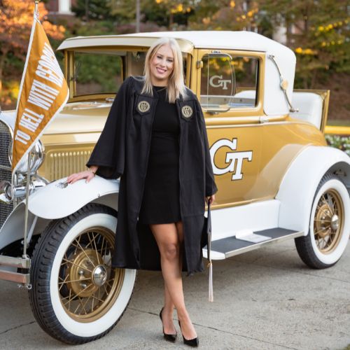 Brown's graduation photo in cap and gown in front of the Ramblin' Wreck