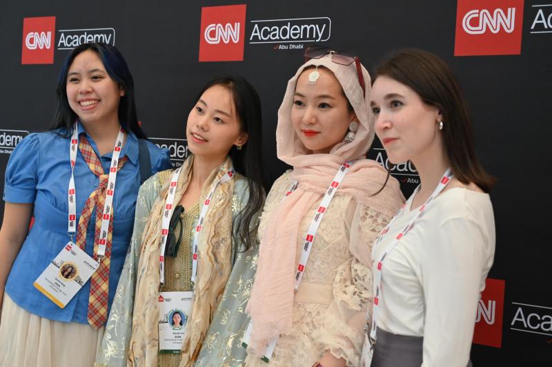 four students posting with their CNN credentials against a CNN backdrop