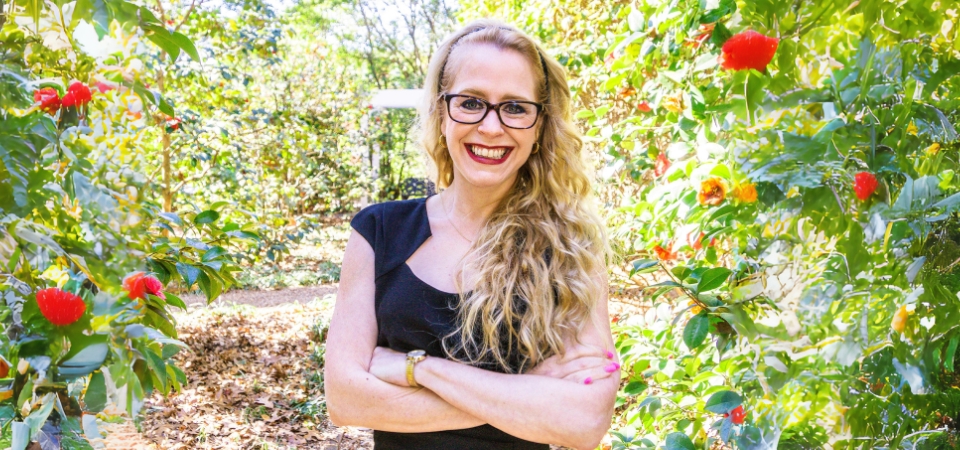 Amanda Murdie standing in a garden with red flowers around her.