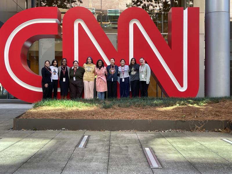 group photo in front of large CNN blocks in front of the building