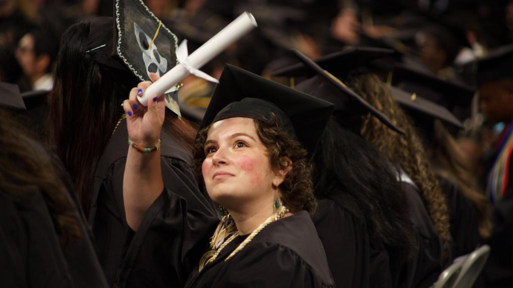 student waving with diploma