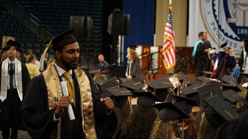students filing out with degrees