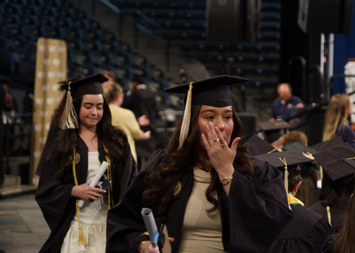 Student wiping tear as she walks out with degree
