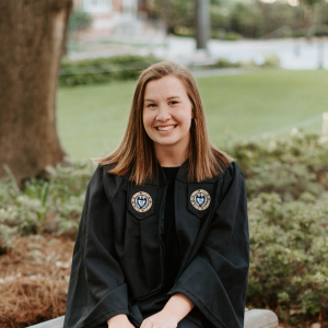 Cara McClain seated outdoors wearing Georgia Tech commencement regalia