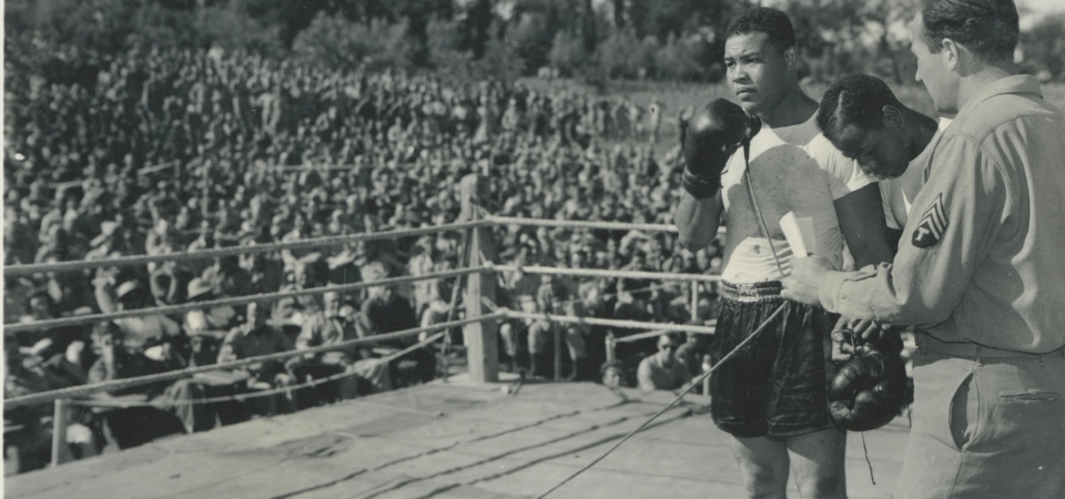Joe Louis speaking to a crowd at an army exhibition match during World War II.