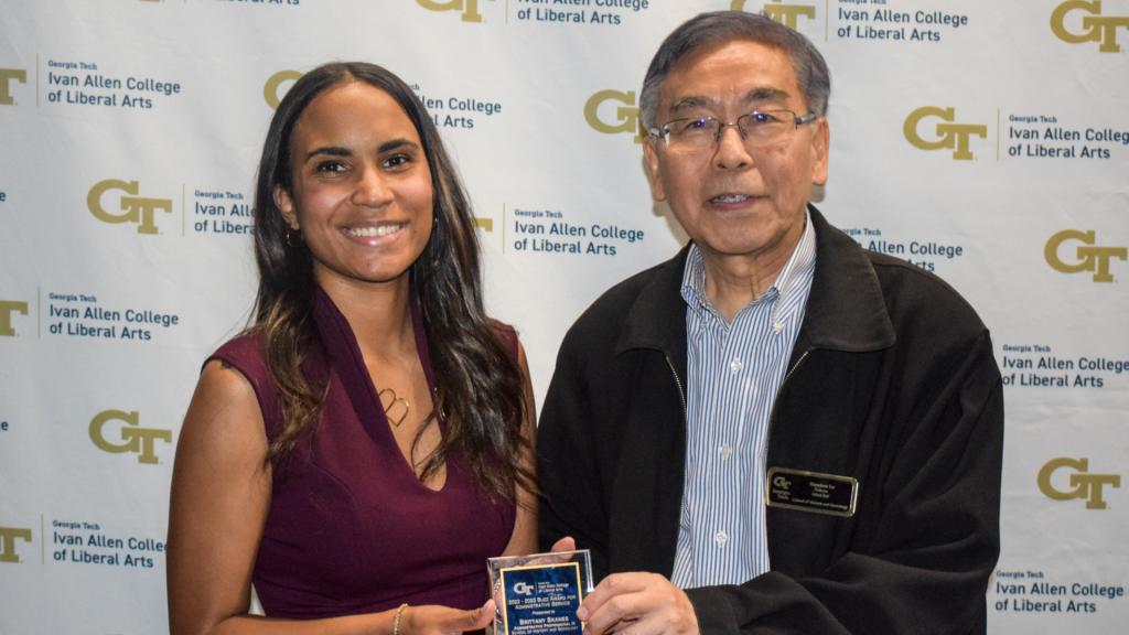 Award recipient smiling holding award.