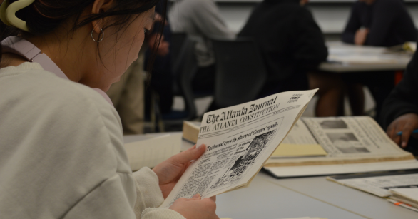 Student reading an AJC article from the archives at a history and sociology workshop