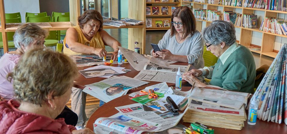 Group of seniors sitting at a table with crafting supplies, smiling.