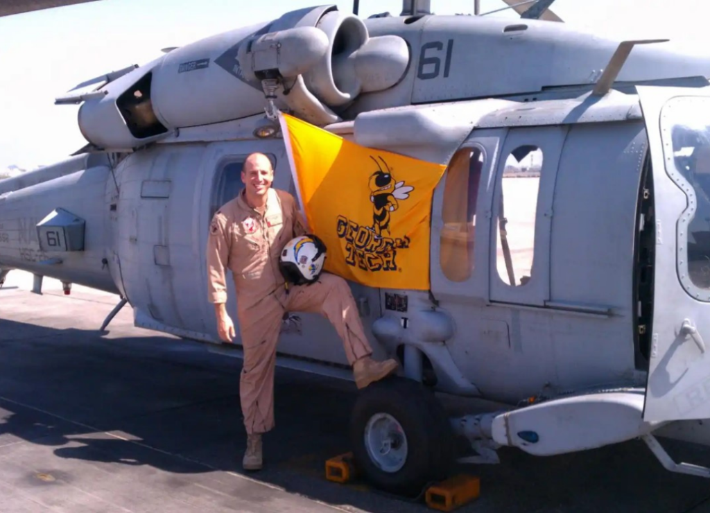 Daniel in front of a helicopter with a Georgia Tech flag