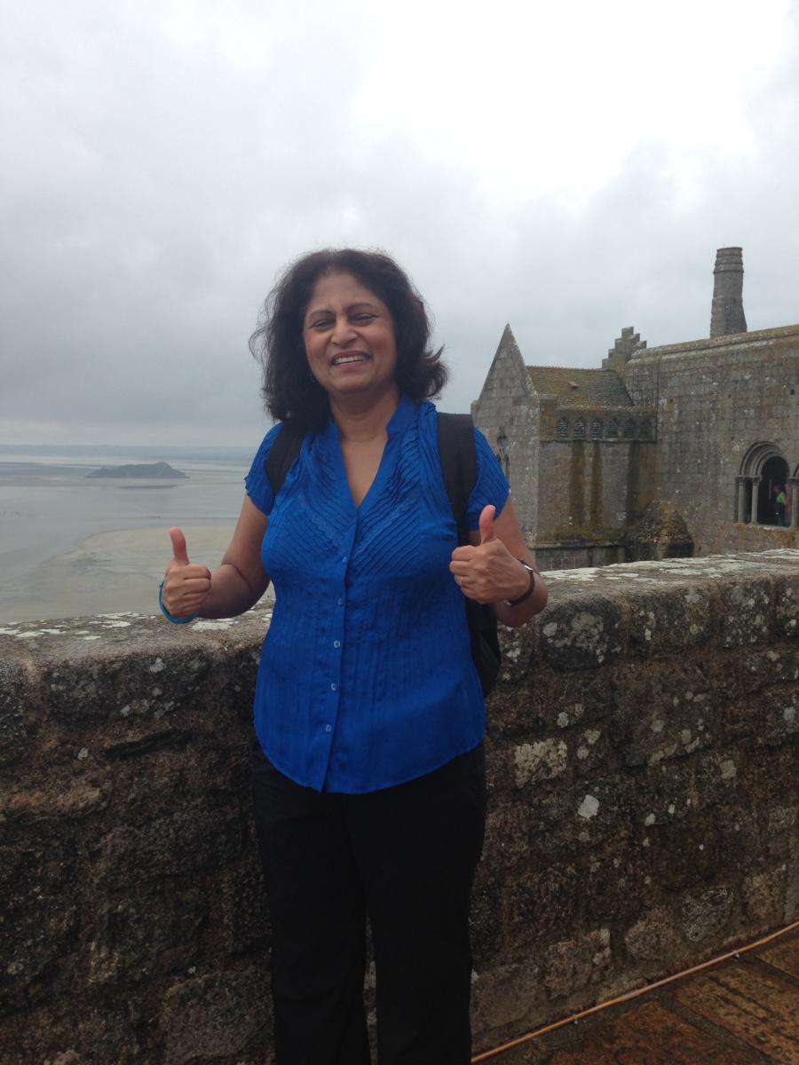 Usha with a thumbs up at a castle.