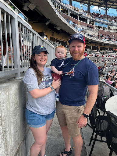 Chris McDermott with his wife and baby at a baseball game.