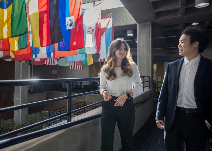 Two students in front of international flags