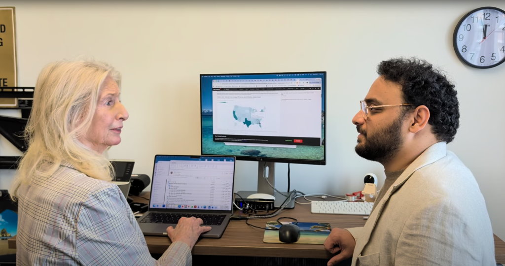 Two Georgia Tech researchers talk in front of a computer showing a U.S. map.