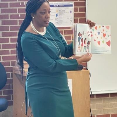 Candace reading a children's book to a class
